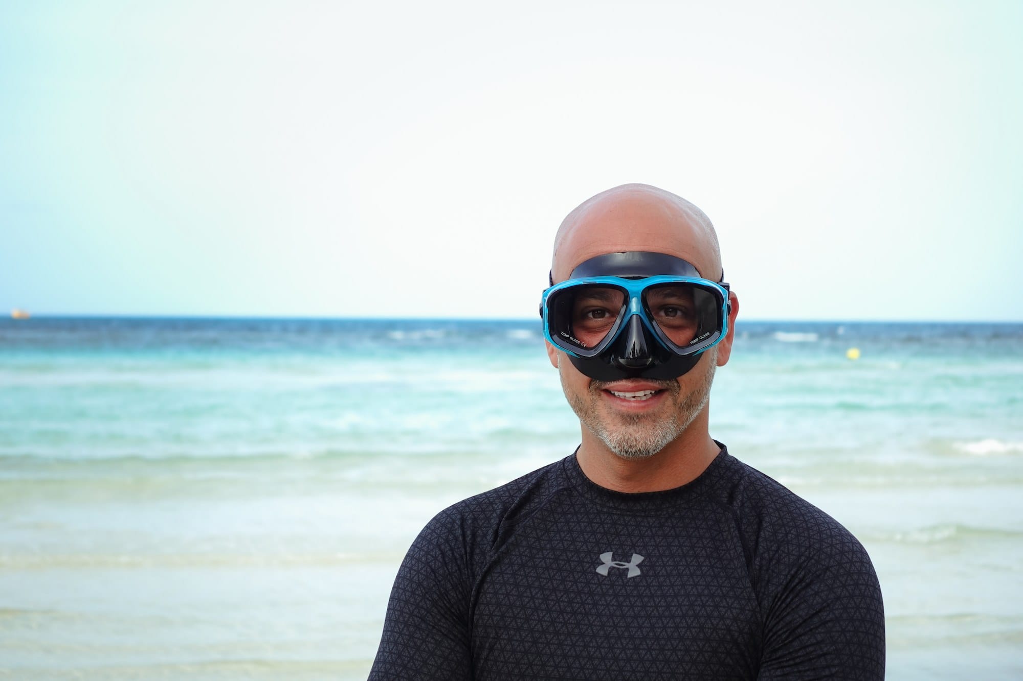Man wearing a prescription snorkel mask with a beach and ocean in the background