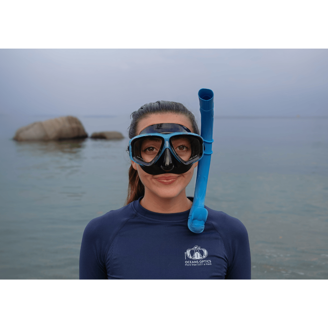 snorkeler wearing an aqua blue prescription snorkeling mask and blue snorkel with an ocean horizon in the background